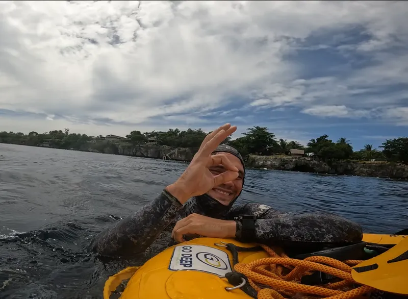 Plongeur souriant fait un signe de la main depuis un bateau jaune