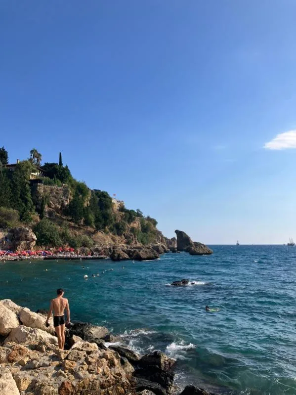 Homme regardant la mer depuis des rochers, paysage côtier ensoleillé