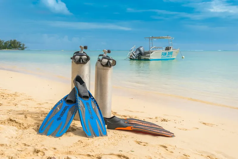 Equipement de plongée sur une plage de sable blanc avec un bateau en arrière-plan