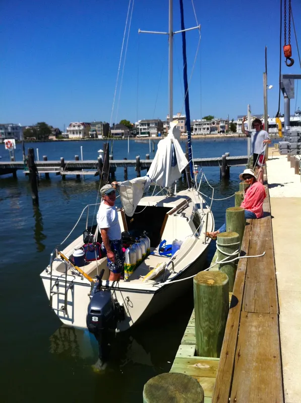 Personnes près d'un petit bateau amarré à un ponton ensoleillé