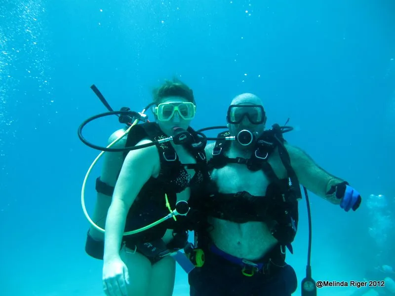 Deux plongeurs avec équipement complet évoluent dans une eau turquoise claire
