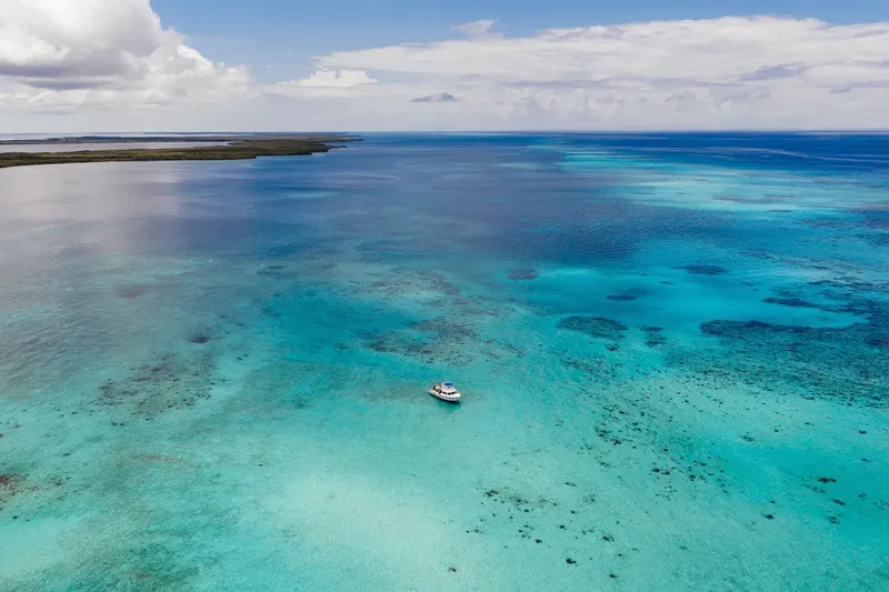 Vue aérienne d'un bateau de plongée sur une mer turquoise et peu profonde