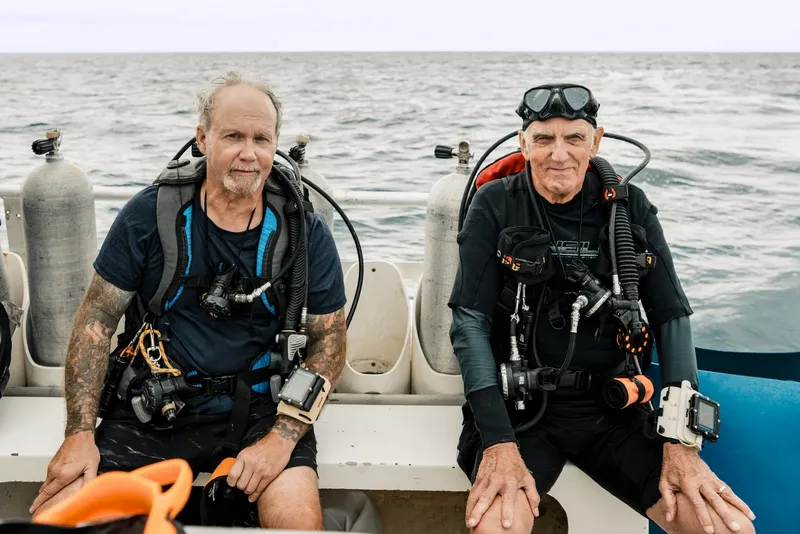Deux plongeurs équipés assis sur un bateau en mer