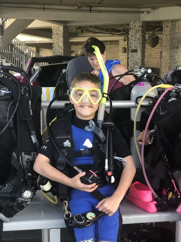 Jeune plongeur équipé d'un masque et d'une combinaison, souriant à la caméra