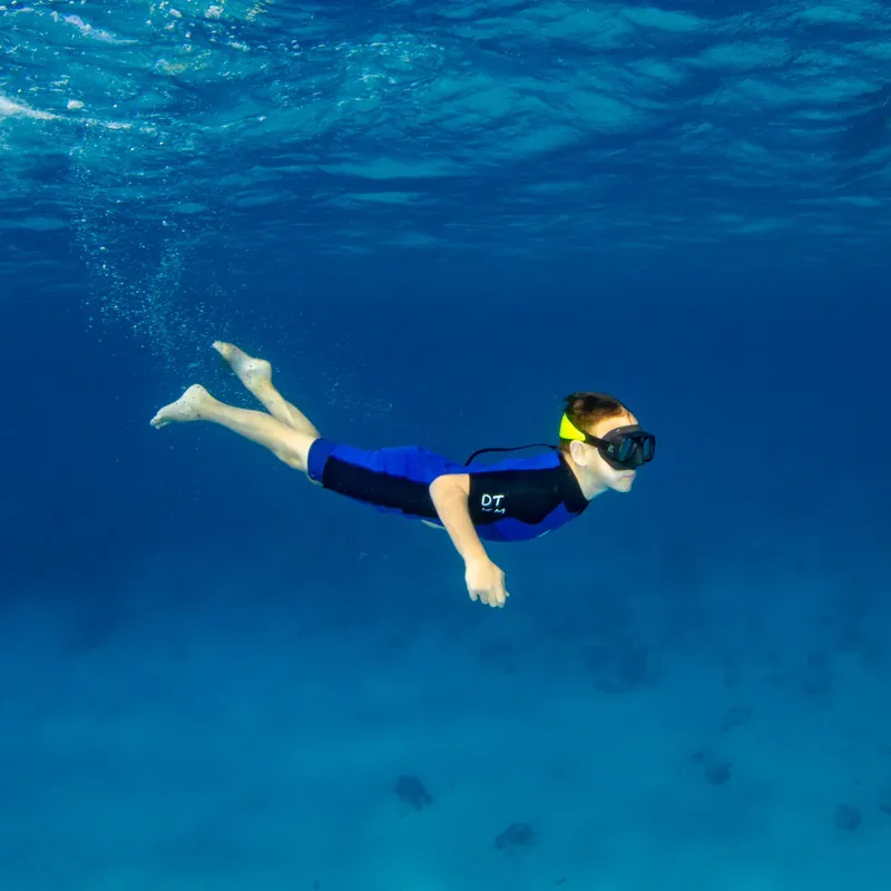 Une personne nageant en apnée dans une eau bleue claire et limpide