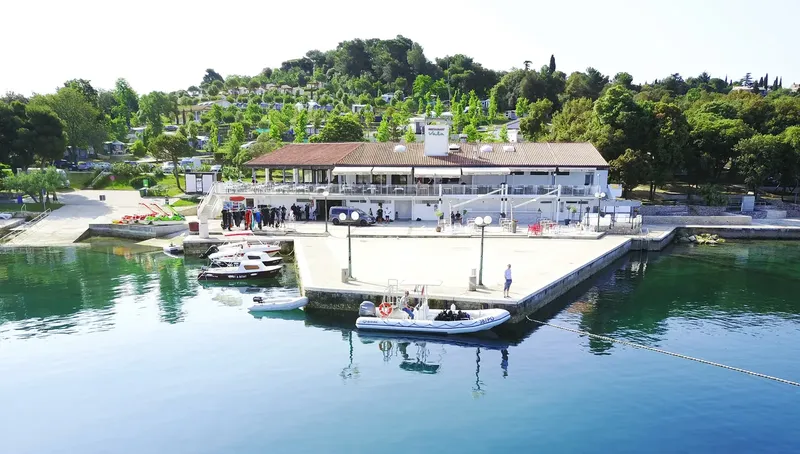Bâtiment blanc avec ponton et bateaux amarrés au bord de l'eau