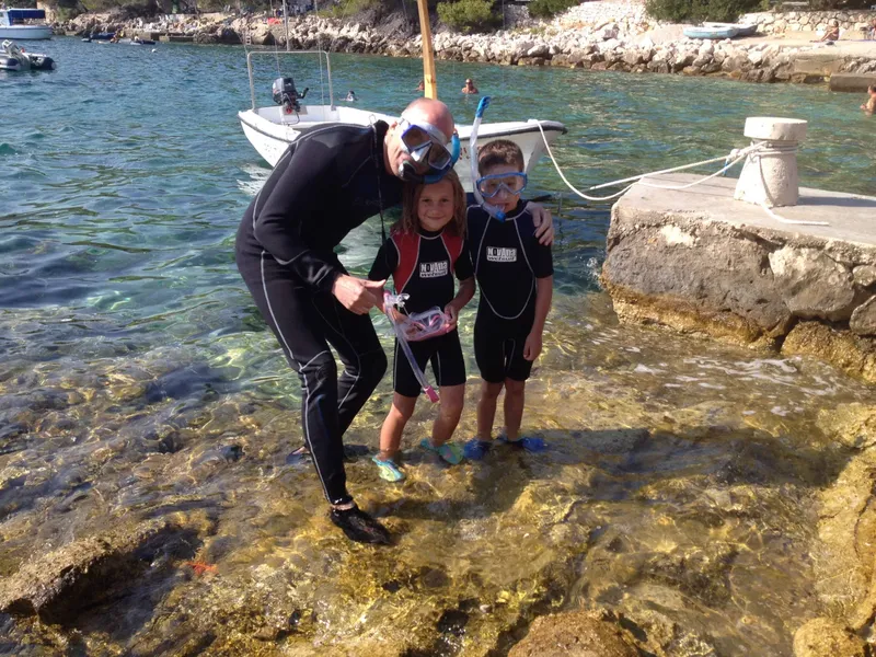 Un moniteur aide deux enfants à enfiler leur matériel de snorkeling