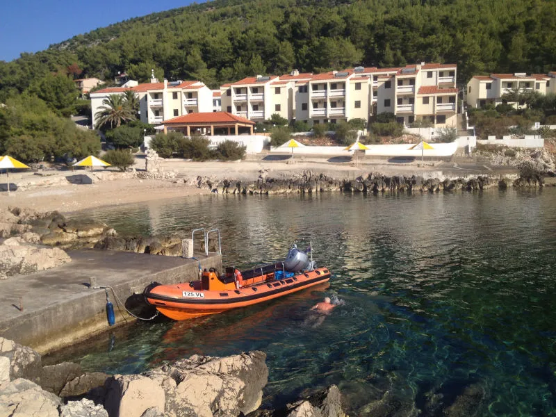 Bateau de plongée amarré devant un bâtiment et une personne nage