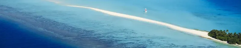 Vue aérienne d'une étendue d'eau turquoise avec un bateau à voile