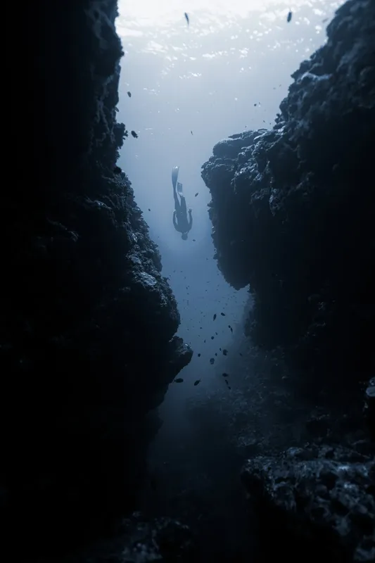 Plongeur en apnée explore une fissure rocheuse sous-marine éclairée