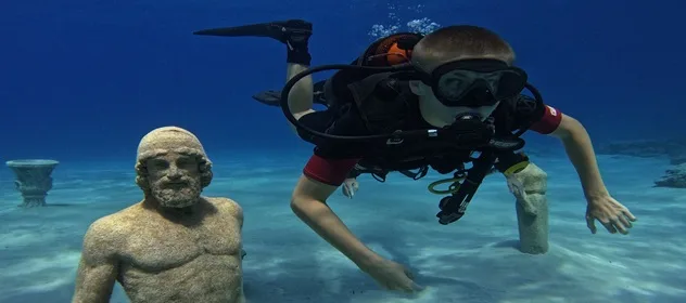 Plongeur explorant des statues antiques sous-marines dans une eau claire