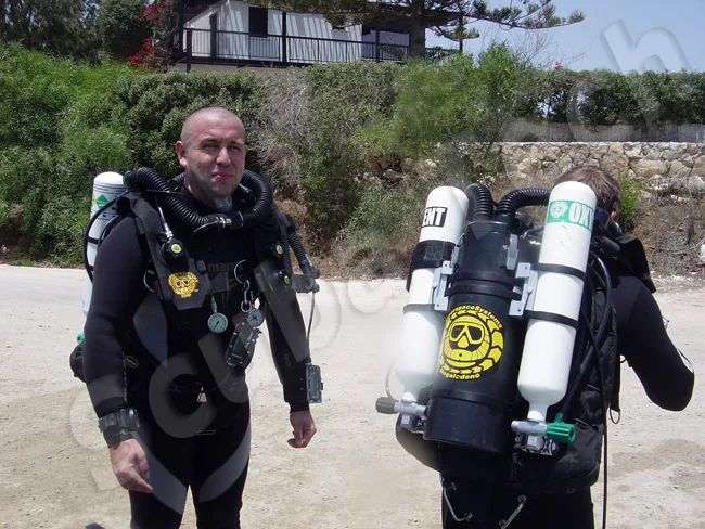 Deux plongeurs équipés se tiennent debout sur un terrain rocailleux