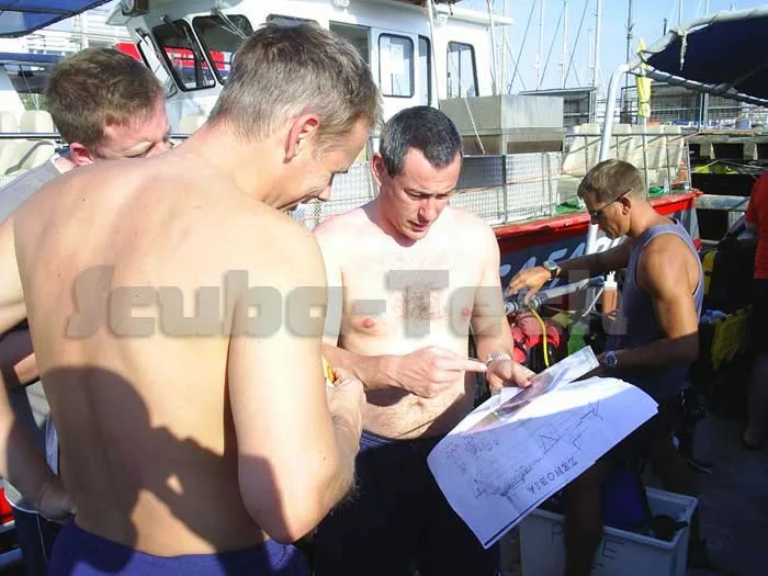 Plongeurs torse nu regardent une carte sur un bateau de plongée