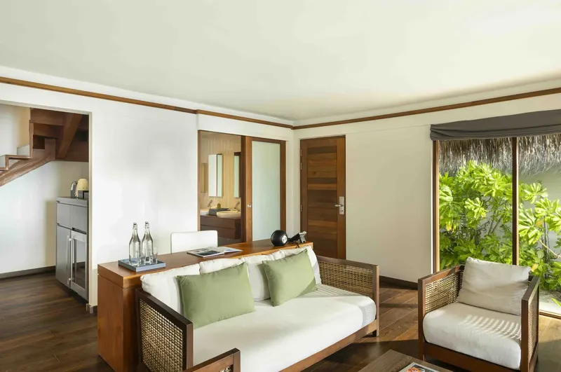 Intérieur d'une chambre avec canapé, bureau et accès à une salle de bain