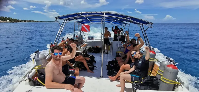 Groupe de plongeurs enthousiastes sur un bateau en mer, équipement visible