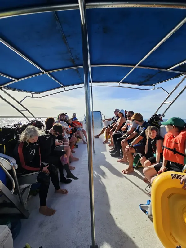 Groupe de plongeurs assis sur un bateau en direction d'un site