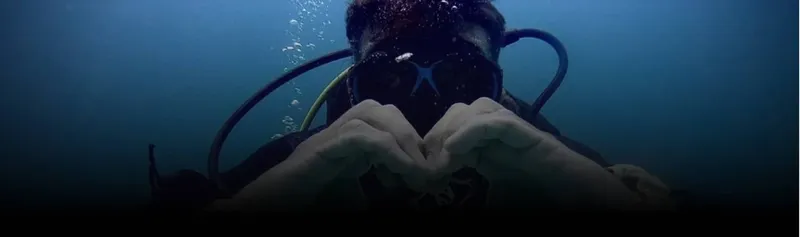 Plongeur souriant formant un cœur avec ses mains sous l'eau