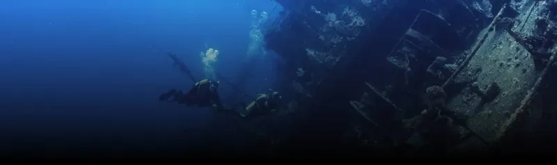 Plongeurs explorant l'épave d'un navire sous l'eau bleu profond