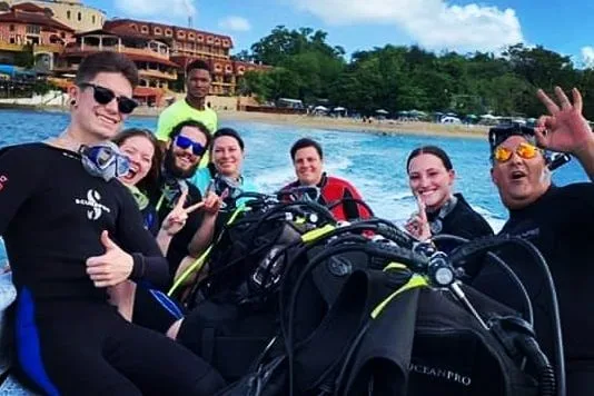 Groupe de plongeurs souriants sur un bateau avec leur équipement