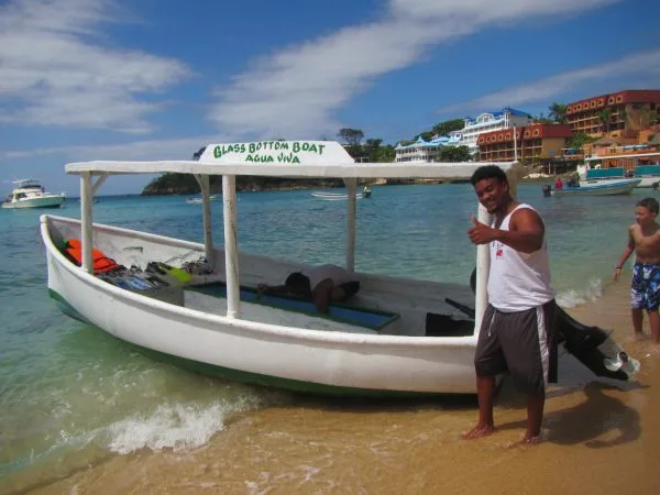 Homme souriant près d'un bateau à fond de verre sur la plage