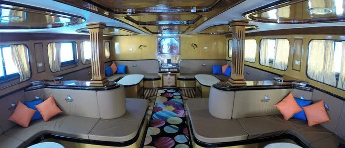 Intérieur d'un bateau de plongée avec banquettes, tables et hublots