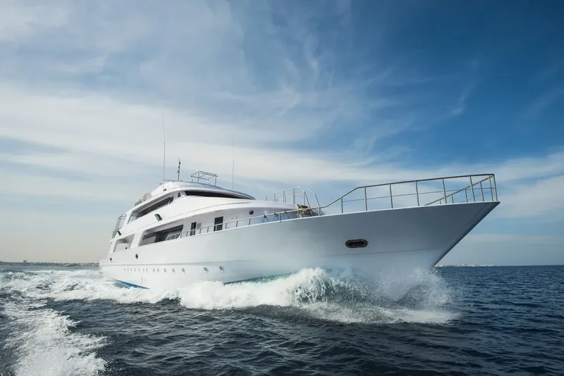 Grand yacht blanc naviguant sur une mer bleue sous un ciel nuageux