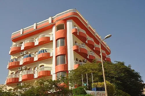 Bâtiment coloré à balcons, végétation, lampadaire et ciel bleu clair