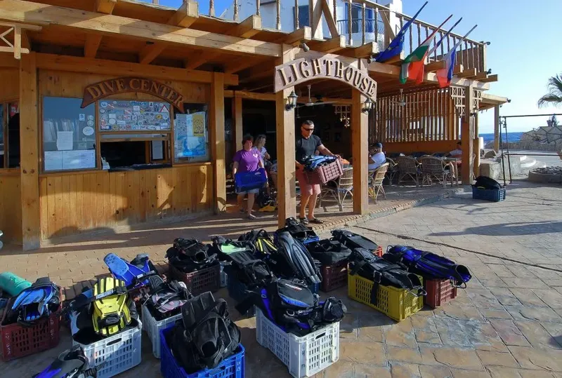 Devant un centre de plongée, des personnes et du matériel sont visibles