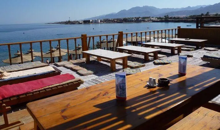 Terrasse en bois avec tables, chaises longues et vue sur la mer