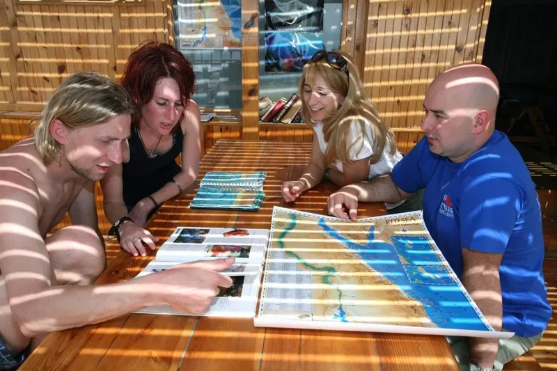 Quatre personnes regardent une carte et des photos de plongée ensemble