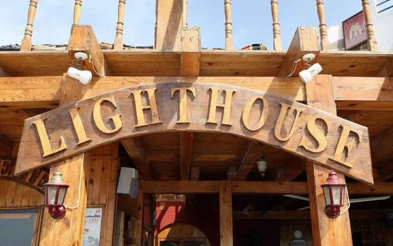 Enseigne en bois Lighthouse au-dessus d'une entrée avec éclairages