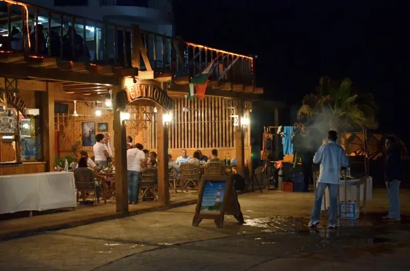 Terrasse éclairée avec des personnes dînant et un barbecue extérieur