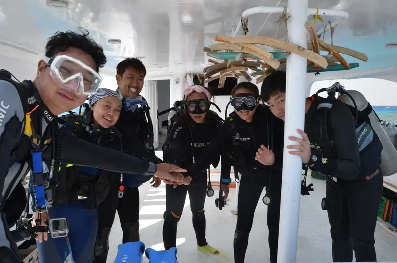 Groupe de plongeurs souriants équipés à bord d'un bateau de plongée