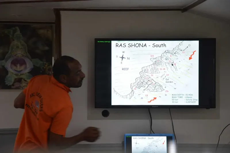 Un homme explique une carte de site de plongée sur un écran