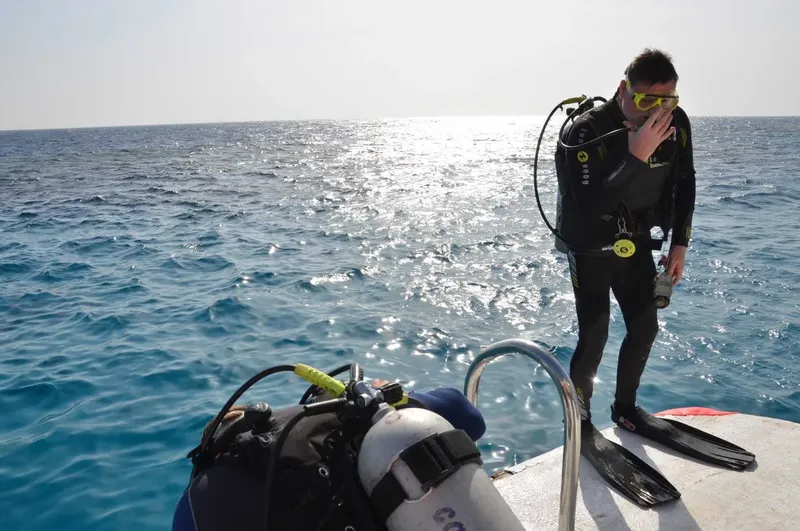 Plongeur en combinaison complète se préparant sur un bateau en mer