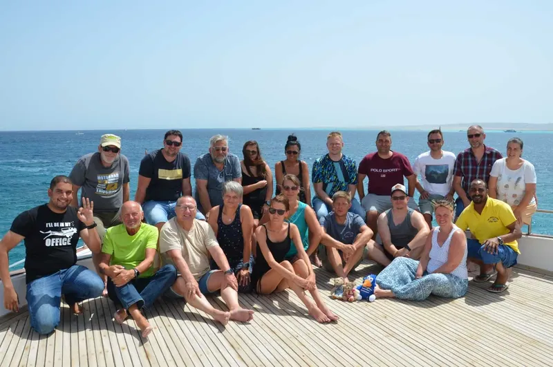 Groupe de personnes souriantes sur le pont d'un bateau en mer