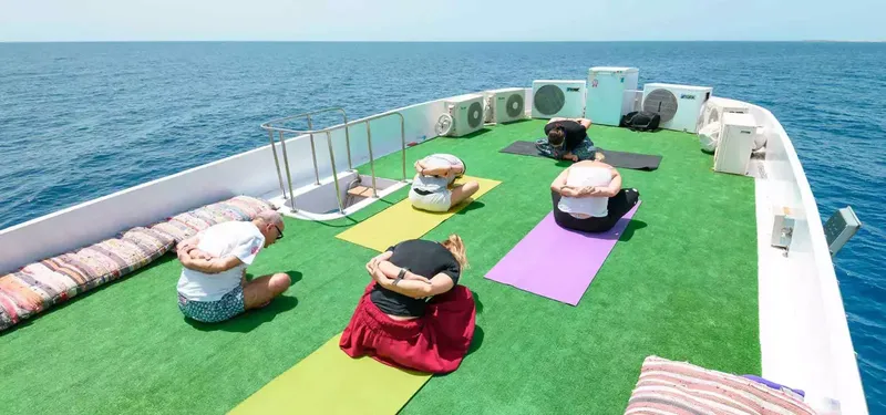 Personnes pratiquant le yoga sur le pont d'un bateau en mer