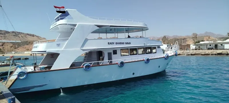 Bateau de plongée amarré au port avec des montagnes en arrière-plan