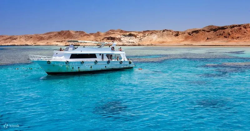 Bateau de plongée amarré dans une eau turquoise, paysage côtier désertique
