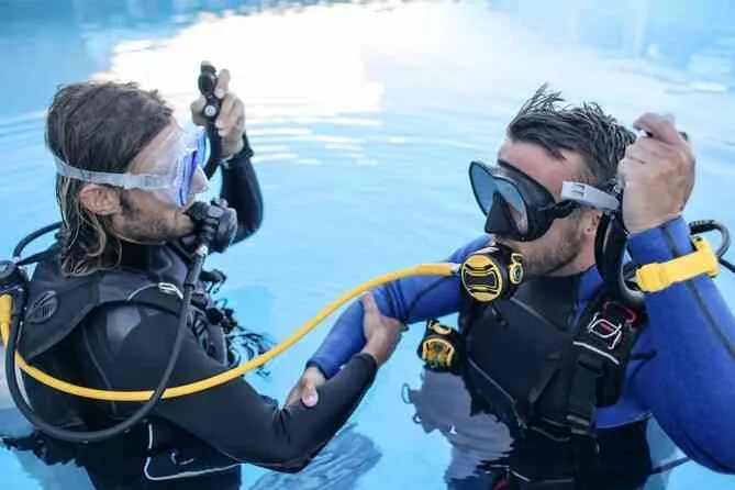 Deux plongeurs vérifient leur équipement au bord d'une piscine