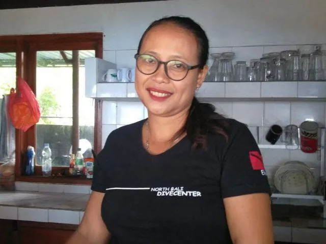 Femme souriante portant un t-shirt avec le nom d'un centre de plongée