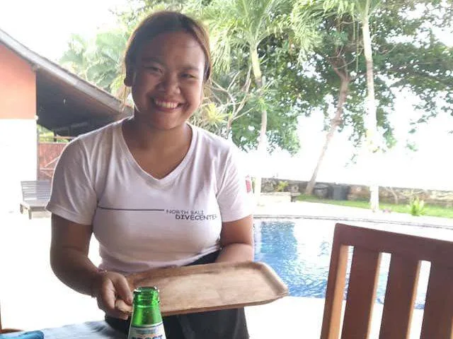 Jeune femme souriante servant une boisson près d'une piscine