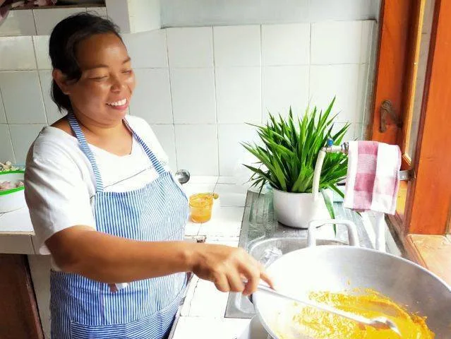 Femme souriante cuisine dans une cuisine lumineuse avec une grande poêle