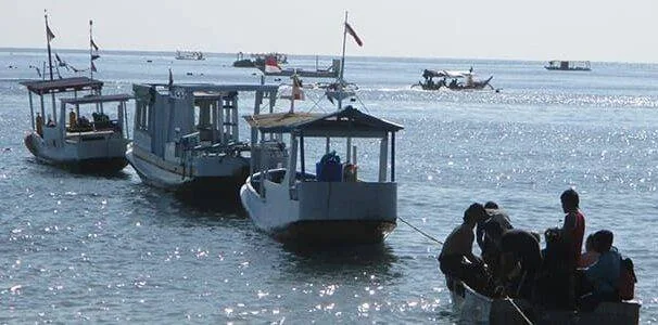 Plusieurs petits bateaux de pêche flottent sur une mer calme