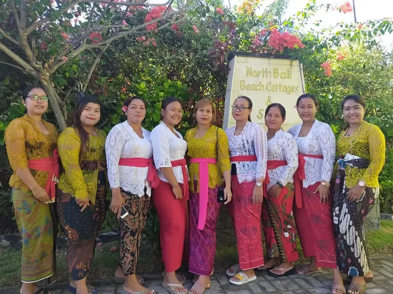 Groupe de femmes souriantes en tenue traditionnelle balinaise devant végétation