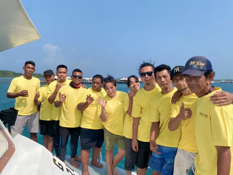 Groupe de personnes souriantes sur un bateau en mer, portant des t-shirts jaunes
