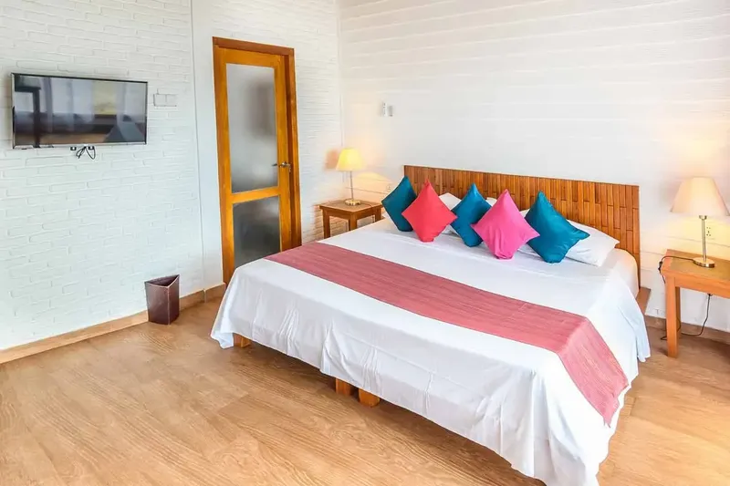 Chambre d'hôtel lumineuse avec un grand lit et des coussins colorés