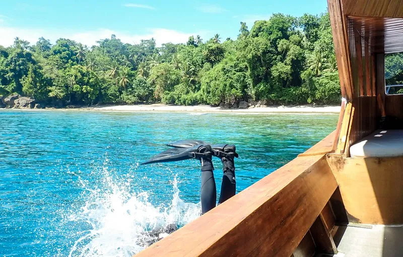 Plongeur s'apprête à entrer dans l'eau depuis un bateau en bois