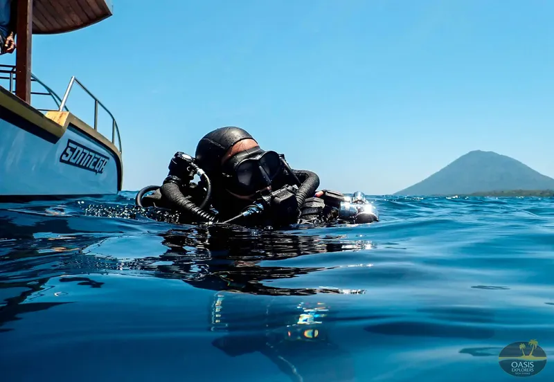 Plongeur en surface près d'un bateau avec un volcan en arrière-plan