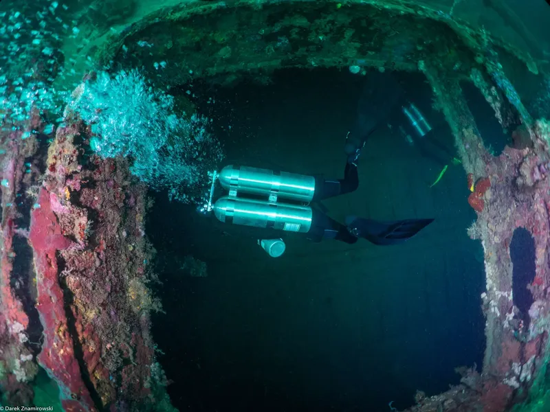 Plongeur explorant l'intérieur d'une épave sous-marine, lumière verte